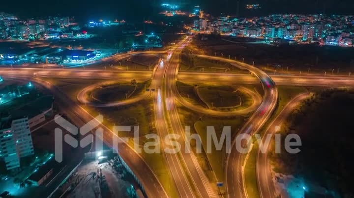 Aerial view of a multi-level stack interchange. Blue yellow neon light. Street lighting. Fast moving cars. Timelapse