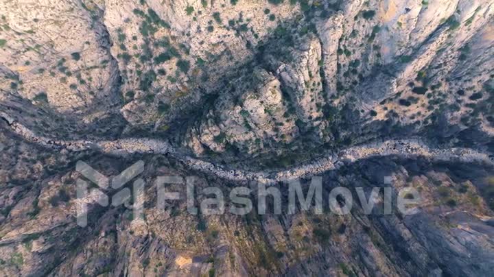 Aerial drone footage of a mountain river in a canyon. Green grass grow along the rocks. High gray rocks. Narrow space.