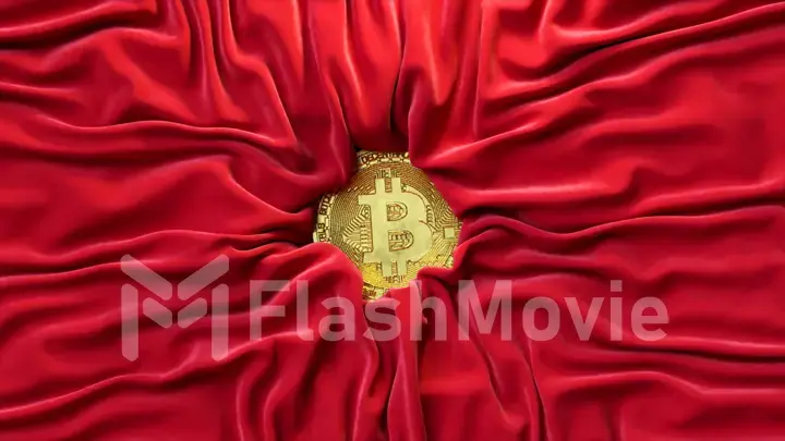 Satin red fabric crinkles around the gold bitcoin. Cryptocurrency concept. Silk. Creases in fabric. Drapery.