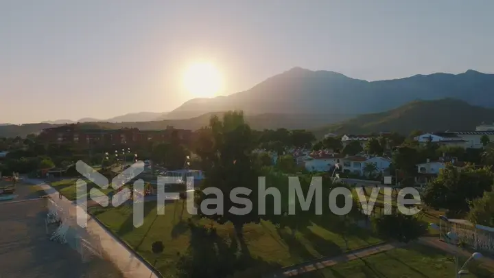 Aerial drone view of the hotel at sunset. Palms. Mountain landscape on the background. Beautiful landscape