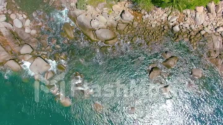 Top view moving up away ocean blue waves crash coastline cliff. Aerial 4k footage in slow motion