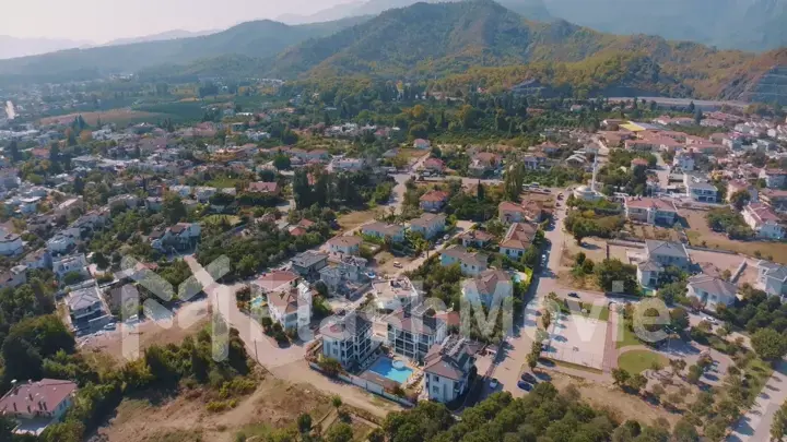 Aerial panorama of small resort town. Hotels, houses and roads. Green hills around. Mountain landscape. Photography