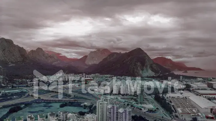 Top view of the big city. Color correction. Mountains and clouds in the background. Road intersection.