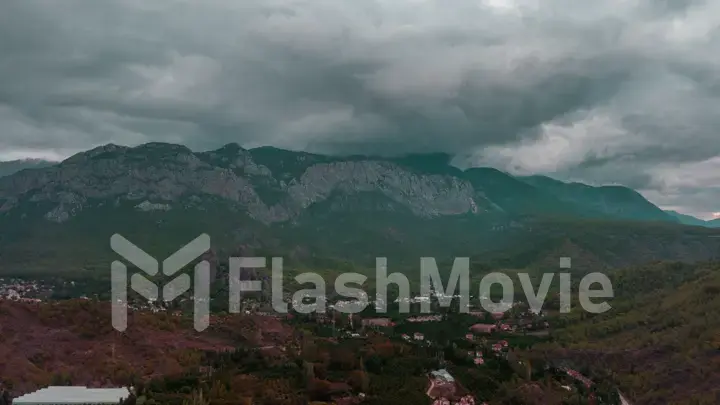 Aerial drone view of a hilly green area. Houses in the green forest. Overcast weather. Gray clouds. Photography