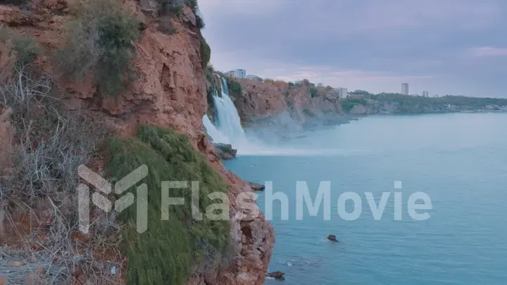 Blue lagoon. Natural stormy waterfall. Plants on the red rocks. Pure water. Aerial drone view