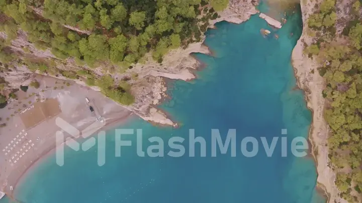 Flight over a large rocky island in the sea. The boat is sailing. Mountains in the background. Aerial drone view