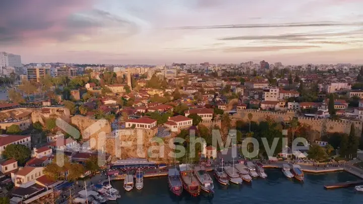 Flight over the seaport at sunset. Boats along the pier. Roofs. Water surface. Seascape. Aerial drone view