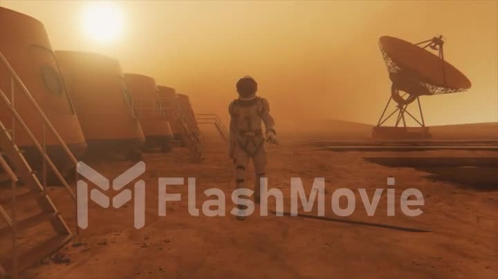 Astronaut on the planet Mars, making a detour around his base. Astronaut walking along the base. Small dust storm. The satellite dish sends data to the ground. Realistic 3D animation