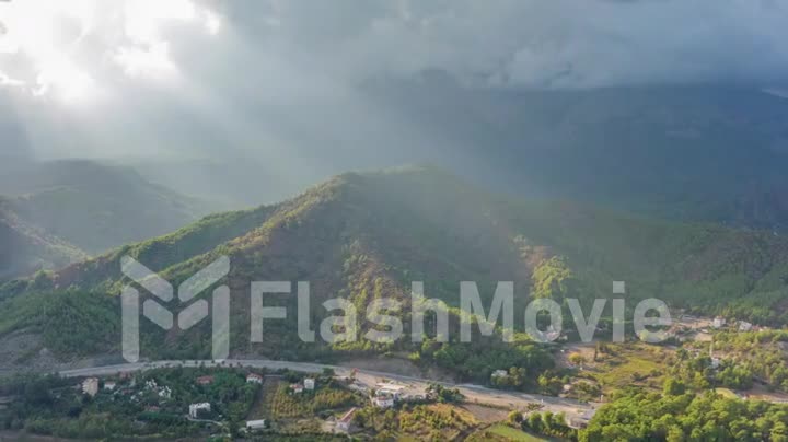 Drone video 4k footage. Flight over a residential area at the foot of the mountains. Green trees. Highway. Sun rays.