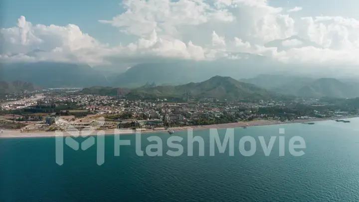 View from the sea to the coastal city. Sunny day. Green mountains. Aerial drone view. Landscape. Coastline. Boats.