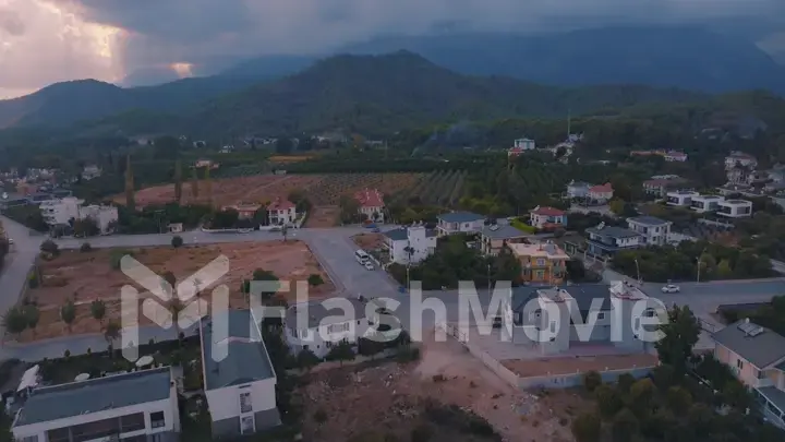 Human and nature concept. Aerial drone view of small town at the foot of the mountain. Green trees. Mountain landscape