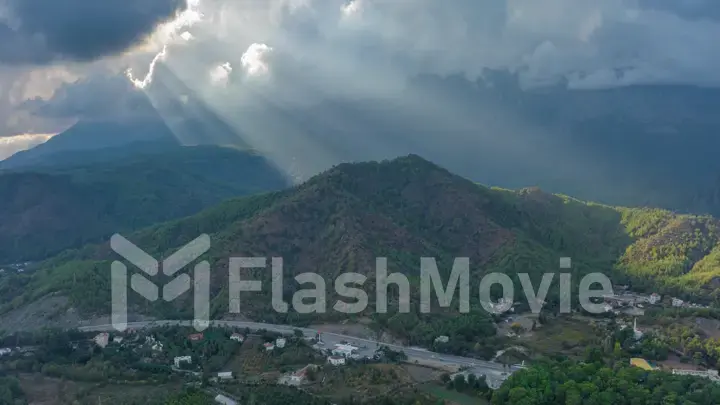 Sunbeams through the clouds. City under the mountain. Top view. Aerial drone view. Landscape.
