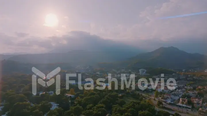 Human and nature concept. Aerial drone view of small town at the foot of the mountain. Green trees. Mountain landscape