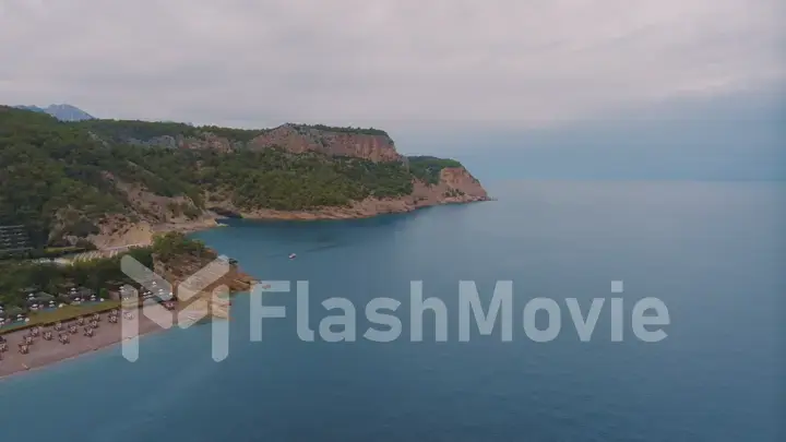 Natural landscape. Aerial drone view of a beach in a blue bay. Rocky coast. Green trees on the rocks.