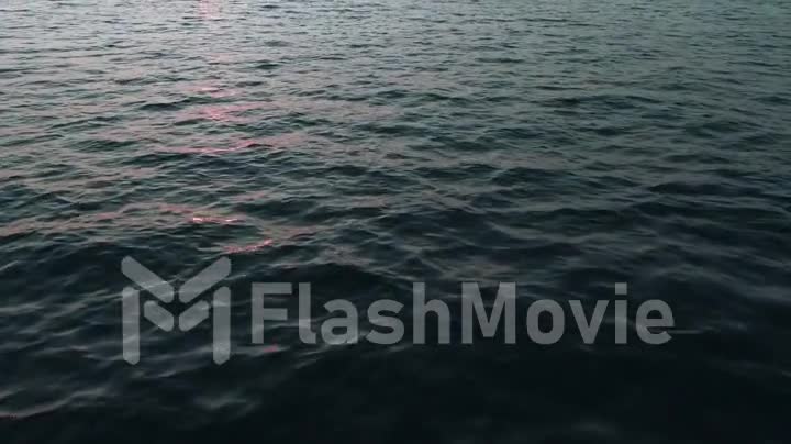 Aerial 4k view. Stunning sunset sun over the sea. Beautiful cinematic scene. Golden sun sets over the horizon, flying above the surface of the water