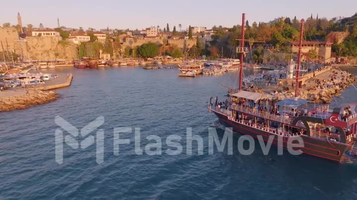 Aerial video footage from the drone of a tourist ship sailing into the bay. Harbor. Historic city in the background.