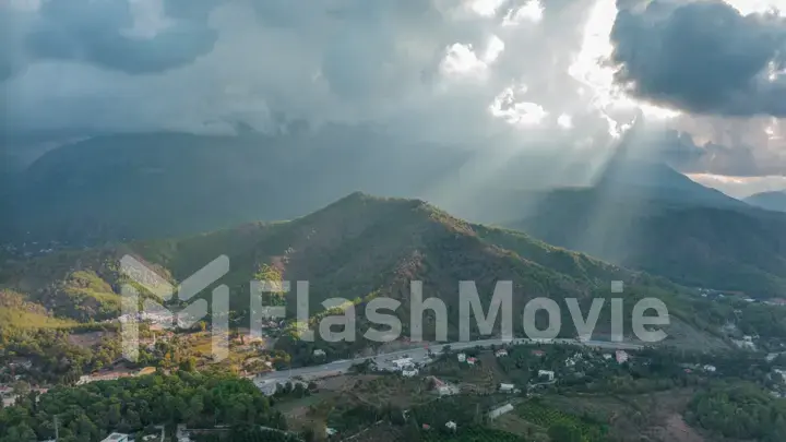 Sunbeams through the clouds. City under the mountain. Top view. Aerial drone view. Landscape.
