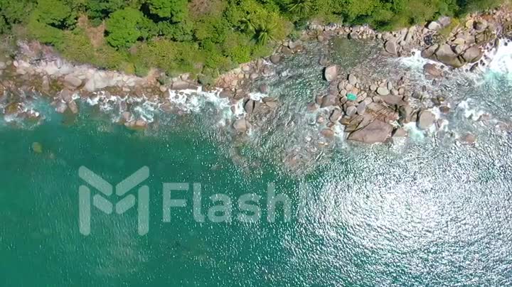Top view moving up away ocean blue waves crash coastline cliff. Aerial 4k footage in slow motion