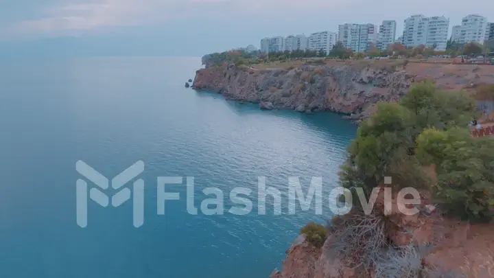 The concept of nature and man. A look from above at the blue sea, rocks and residential buildings on the shore. Riviera