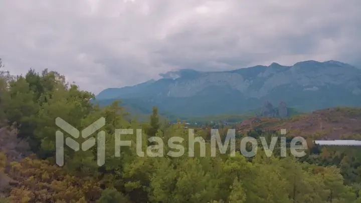 Cloudy weather. Aerial view of a rocky hill. Green trees. Human and nature. Mountain landscape. Photography