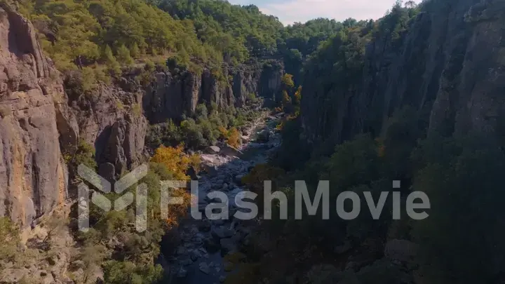 Aerial drone view. Top view of the mountain river. Green trees and shrubs on the rocks. Blue sky white clouds