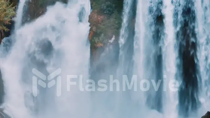 Aerial drone view of a natural waterfall close-up. Spray. Foam. Green vegetation on the rocks. Natural element.