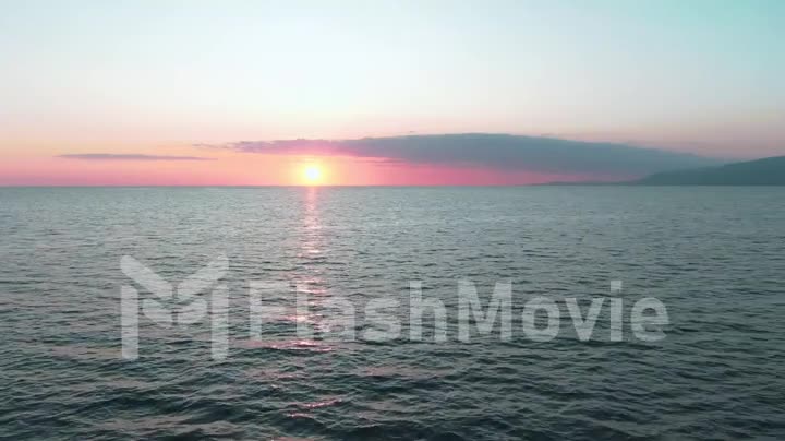 Aerial 4k view. Stunning sunset sun over the sea. Beautiful cinematic scene. Golden sun sets over the horizon, flying above the surface of the water