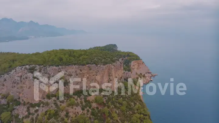 Natural landscape. Aerial drone view of a beach in a blue bay. Rocky coast. Green trees on the rocks.