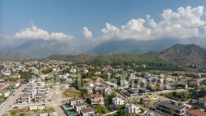 Top view of the big city. Residential houses. Urbanization. Green mountains and clouds in the background. Photography