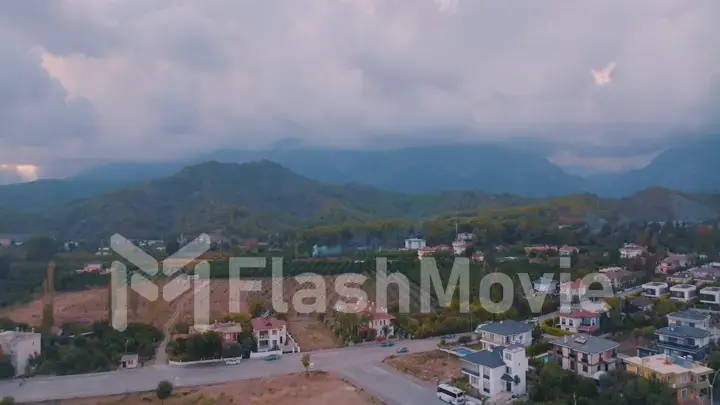 Top view of small resort town. Hotels, houses and roads. Green hills around. Rooftops. Panorama.