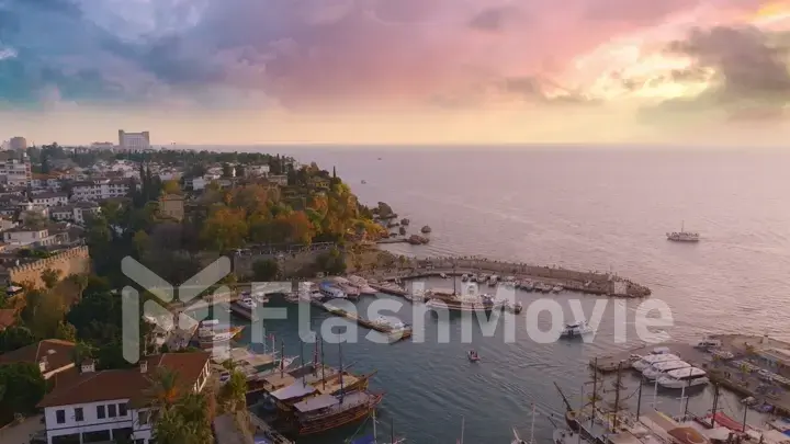 Flight over the seaport at sunset. Boats along the pier. Roofs. Water surface. Seascape. Aerial drone view