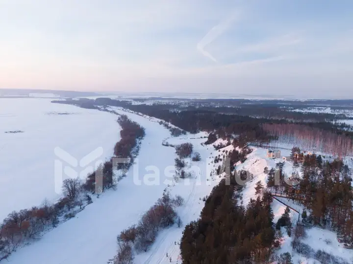 The Aerial view of snow-covered forest in time of sunny winter evening.