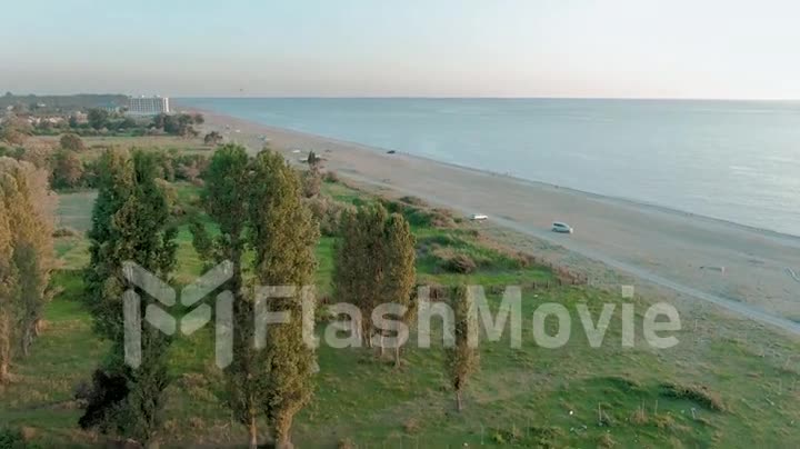 Aerial 4k top view of a beautiful tropical beach and sea waves. Flying over the sandy beach at sunset.