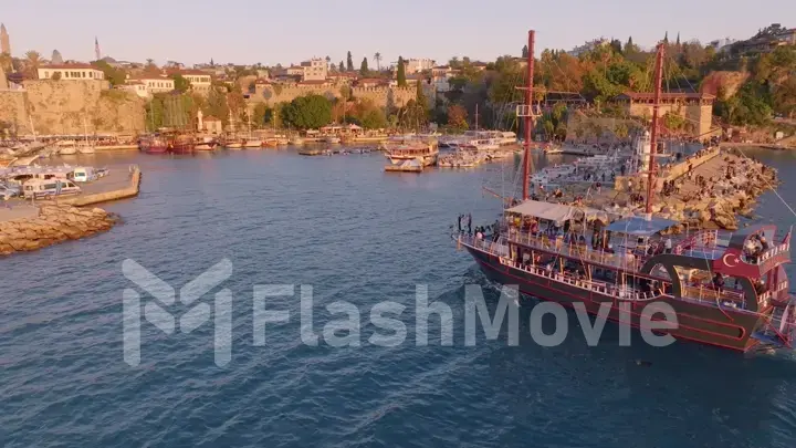 Aerial drone view of a tourist ship sailing into the bay. Harbor. Historic city in the background.