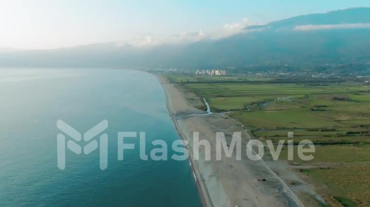 Aerial 4k top view of a beautiful tropical beach and sea waves. Flying over the sandy beach at sunset.