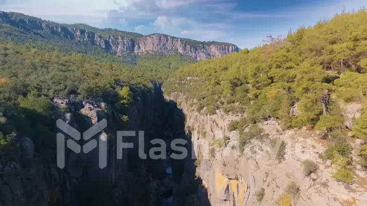 Aerial drone view. Top view of the mountain river. Green trees and shrubs on the rocks. Blue sky white clouds