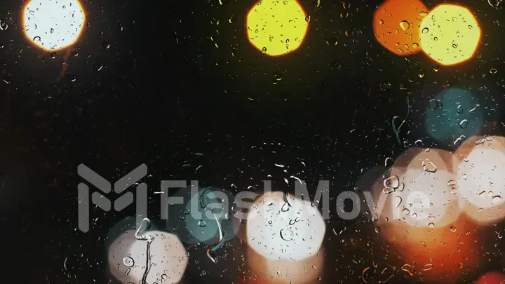 Raindrops on a car window with beautifully blurred background of street traffic lights