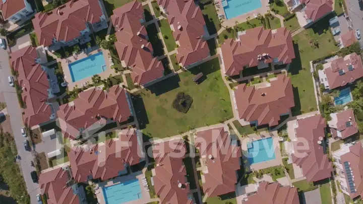 Aerial drone view of the hotel territory. Bungalow rooftops, swimming pools, green lawns and palm trees.