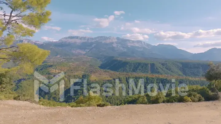 Top view. Aerial drone view of flight over the hills. Mountain landscape. Blue sky white clouds. Green trees.