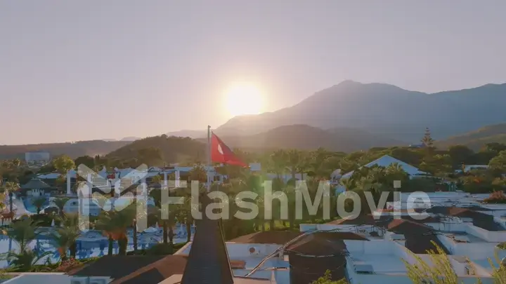 Turkish flag at sunset against the backdrop of the hotel. Swimming pool and palm trees. Mountain. Photography