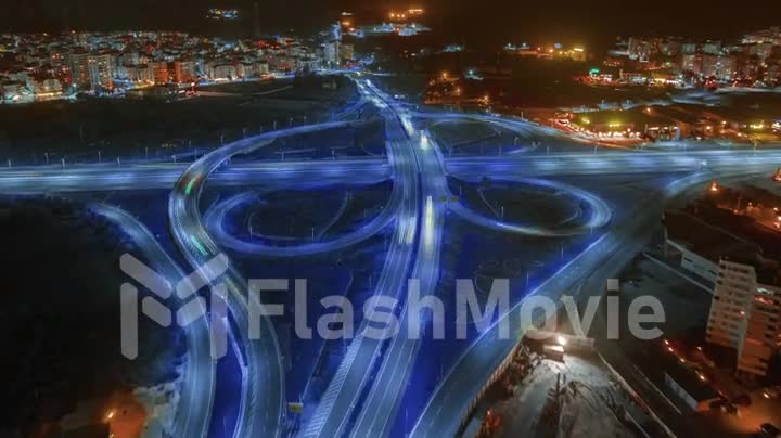 Aerial drone video footage multi-level intersection. Neon blue night lighting. Cars. City illumination. Timelapse