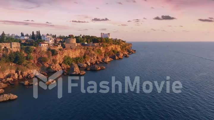 Aerial drone footage flight over the sea at sunset. Ancient fort on the shore. Historical place. Seascape.