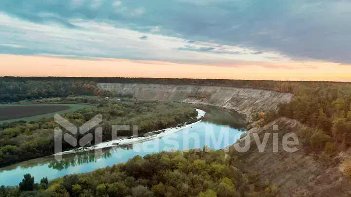 Colorful nature at dusk, the river bends along the mountains and forests, colorful sunset, 4k aerial view