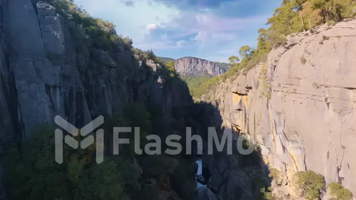 Aerial drone view. Top view of the mountain river. Green trees and shrubs on the rocks. Blue sky white clouds