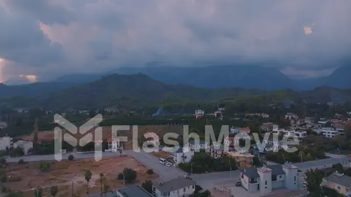 Human and nature concept. Aerial drone view of small town at the foot of the mountain. Green trees. Mountain landscape