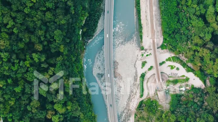 Aerial 4k view. Straight down aerial shot on bridge or raised up road connecting two sides of lake or bay through beautiful blue water. Concept logistics and transportation. Cars on travel road trip