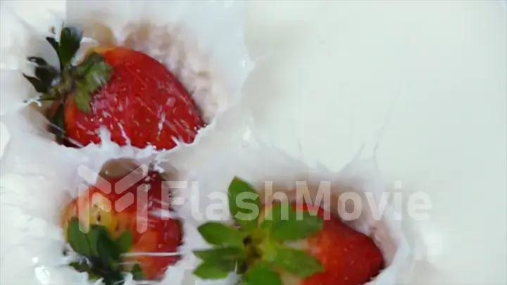 Fresh tasty strawberries falling into cream in slow motion