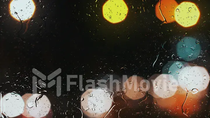 Raindrops on a car window with beautifully blurred background of street traffic lights