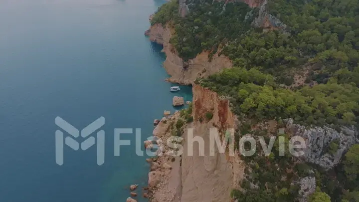 Beautiful seascape. Top view of a rocky shore covered with green trees. Blue water. Aerial view. Photography