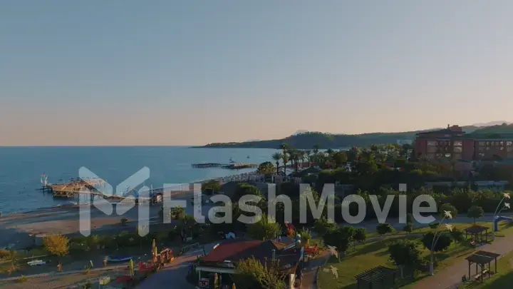 Sunset against the backdrop of a mountain landscape. Aerial drone view of a tourist town by the sea.